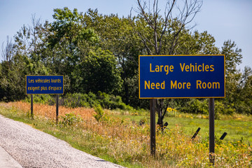 French, English Information Road Signs, large vehicles need more space. on Canadian rural country roadside, forest trees background, Ontario, Canada