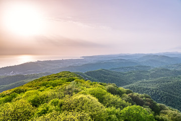 Layers of mountains and the sea in a haze in the light of the sunshine. View from Mount Akhun, Sochi, Russia.