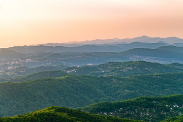 Layers of mountains and the Green valley with the city Sochi in the sunshine. View from Mount Akhun, Sochi, Russia.