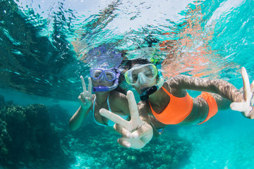 two Young girls snorkeling in blue clear waters having fun at caribbean beach