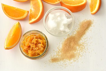 Natural orange body or lip scrub with coconut oil and brown sugar, flat lay on white background....