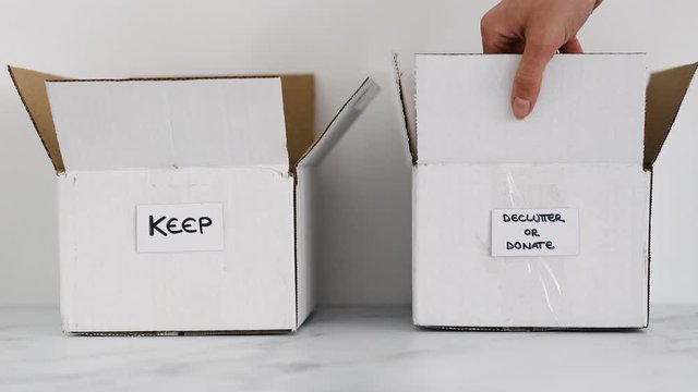 white storage box to sort objects to keep and hand palcing another one for items to declutter or donate