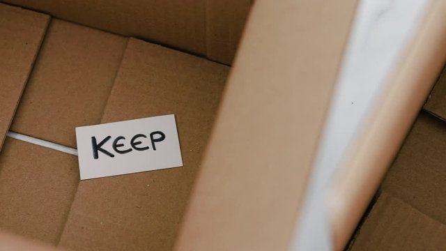 white storage boxes to sort between objects to keep and those to declutter or donate with respective labels camera panning around the scene