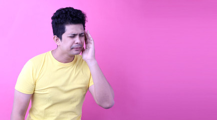 Portrait of a handsome ,Asia man with a headache on pink background in studio With copy space.