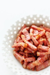 Fried bacon in white bowl on white background with copy space