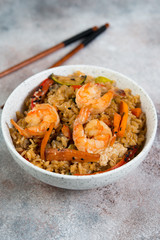Chahan fried rice with egg, vegetables and shrimp on the lighter concrete background . Vertical photo.