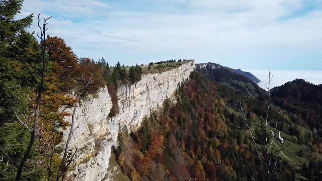 Pan up on cliff wall at Grenchenberg in Switzerland surrounded by autumn colored trees