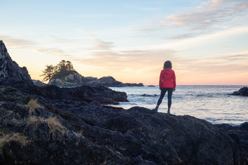 Wild Pacifc Trail, Ucluelet, Vancouver Island, BC, Canada. Girl Enjoyin the Beautiful View of the Rocky Ocean Coast during a colorful and vibrant morning sunrise.