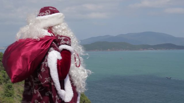 Russian Santa Claus with a bag of gifts walks along the seashore.