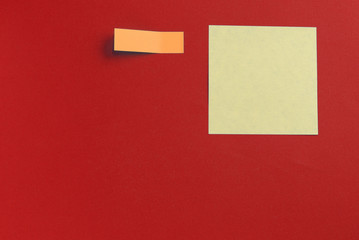 Yellow and orange sticker notes on a dark red background close up