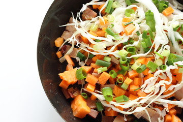 Chopped cabbage, carrot, spring onion, bacon on frying pan