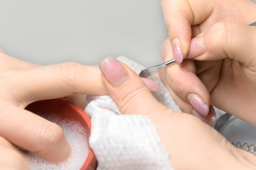 Obraz na płótnie Canvas Nail Care Procedure. Nail salon, manicurist removes cuticles from a woman's fingernails