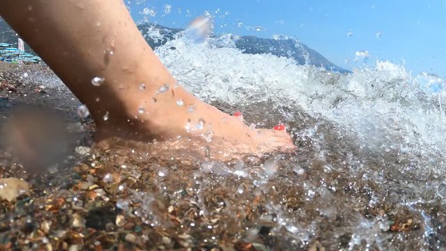 The sea washes the feet of a girl on the seashore. Pebble beach, relaxation and sale, copy space, timelapse