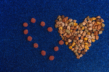 Natural multicolored chocolate pebbles. Tasty sweets in the shape of stones. Heart. Round sweet caramel, pink sugar candies. Background made in trendy classic blue color of the year 2020. Top view