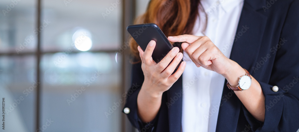 Wall mural closeup image of a businesswoman holding and using mobile phone