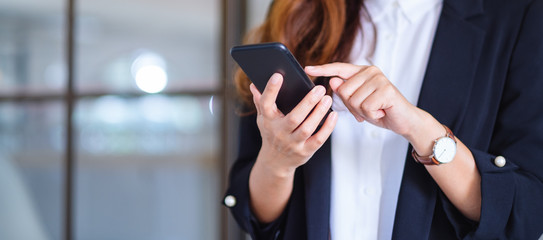 Closeup image of a businesswoman holding and using mobile phone - obrazy, fototapety, plakaty