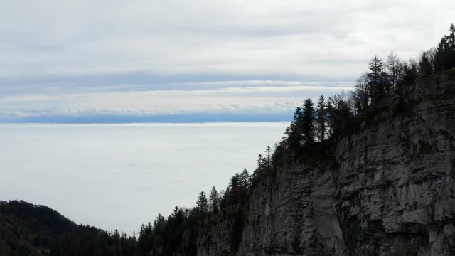 Aerial footage of flight forward over tree covered terrain towards sea of fog at Grenchenberg in Switzerland