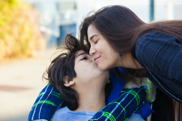 Disabled little  boy giving teen girl kiss on cheek