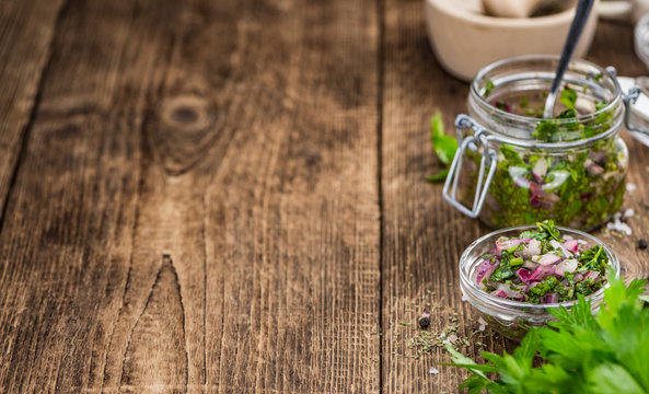 Wooden table with Chimichurri (detailed close-up shot; selective focus)