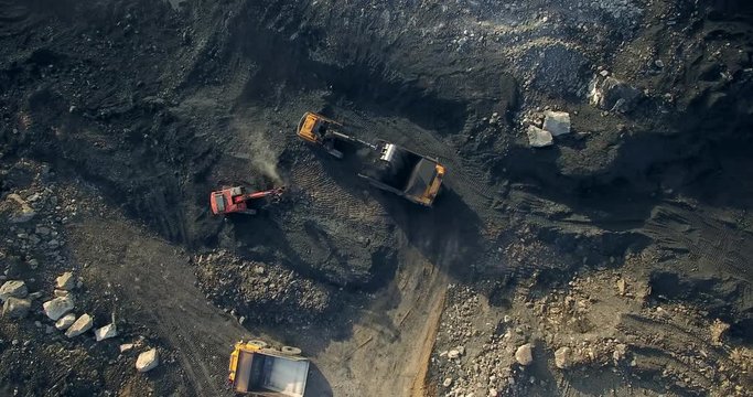 The view from above is the excavator loading the yellow truck with coal. Drone landing over coal quarry