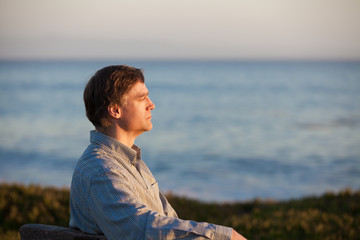 Profile of Caucasian man in 50s by ocean at sunset