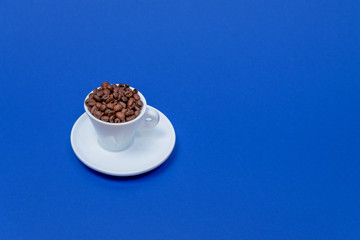 Obraz na płótnie Canvas offee beans in a coffee cup isolated from above on a blue background. with clipping path.