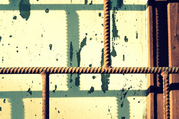 Old painted window behind a rusty bars on a sunny day. Toned abstract background