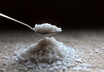 Large crystals of natural rock salt in a spoon were recruited from a hill of salt.