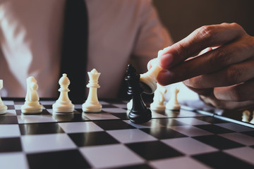 Closeup photo of businessman playing chess and beating black king