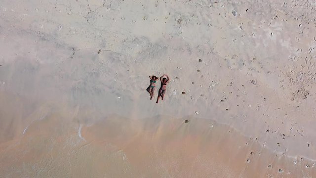 Girls in bikini sunbathe lying on white sand of exotic beach washed by waves of sea under syn rays of a hot summer day in Dominican Republic