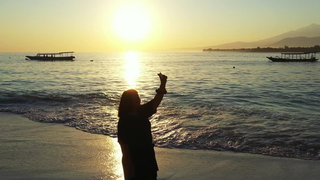 Woman taking selfie using phone on beach at sunset smiling , enjoying nature and lifestyle on vacation