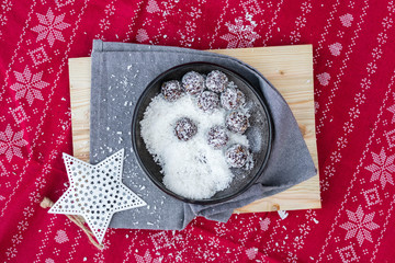 Sweet vegan coconut, cocoa, banana, dates, nuts energy protein balls. On Christmas table cloth background. Vegetarian healthy dessert food. 