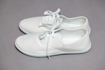 Pair of white sneakers standing on gray background