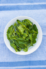 Green spinach leaves soaked and washed in water in bowl. Vegan, vegetarian healthy food. 