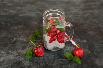 Fresh strawberries close-up while in a cocktail jar. Ripe strawberries in a summer refreshing cocktail on a dark background and copy space.
