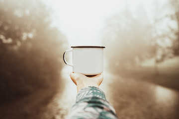 Mug mockup with coffe in traveler's hand.