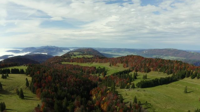 Epic aerial footage of slow climb and turn over autumn colored forest covered mountains at Grenchenberg in Switzerland