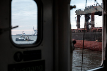Blick aus Bullauge auf Boot und Hafen mit Kran