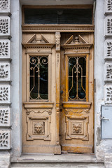 Old ornate yellowish wooden front door with windows