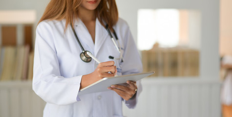 Cropped shot of young doctor checking patient chart while using digital tablet