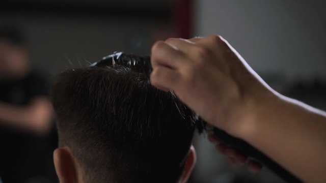 Client during beard shaving in barber shop. Hairdressing services. man cuts hair at a hairdresser-stylist in barbershop. scissors comb close-up Details of trimming. Cropped closeup  barber trimming