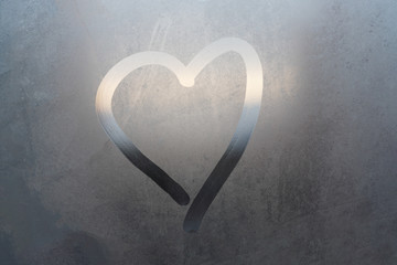 Inscription heart on the sweaty glass. heart drawn on a misted glass window on the grey background. symbol of loneliness and love painted on the misted glass