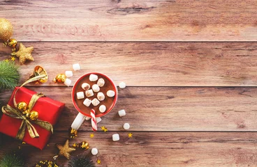 Poster a cup hot chocolate with marshmallow, red gift box, pine cone decoration and shining golden star flakes, copy space for merry Christmas and happy new year concept background. © p-fotography