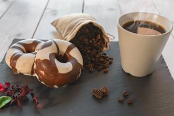 Desayuno con café y donuts sobre plato de pizarra