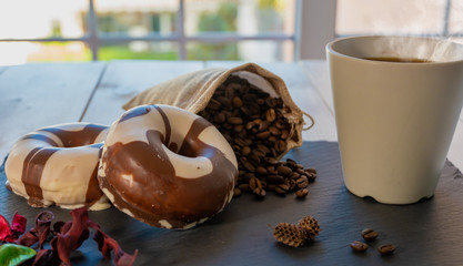 Desayuno con café y donuts sobre plato de pizarra