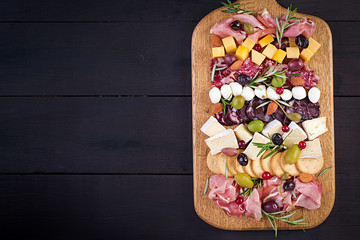 Antipasto platter with ham, prosciutto, salami, cheese,  crackers and olives on a wooden background.  Christmas table. Top view, overhead