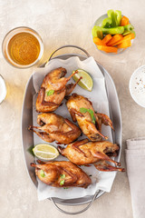 Tasty fried quail with herbs, celery, carrots and sauce on a light background.