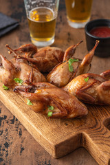 Delicious fried roasted quails with herbs, spices and beer. Grilled quails. Holiday Christmas and Thanksgiving meal concept.