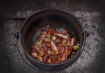 Close-up of cooking meat in a cauldron on coals, picnic, tourism