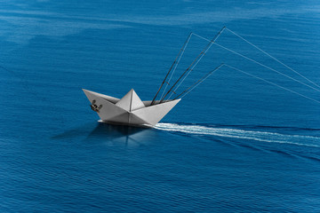 Big game fishing concept. Paper trolling boat with three fishing rods in the blue sea with wake, photography